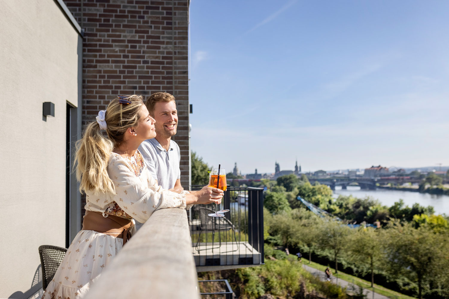 Ein junges Paar auf dem Balkon mit Stadtblick und Aperol